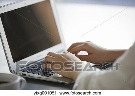 Stock Image - Japanese woman with laptop in a stylish cafe. Fotosearch