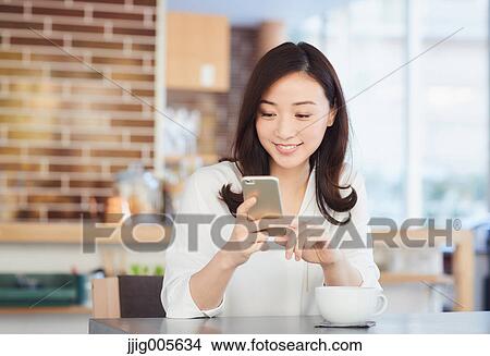 Japanese woman with smartphone in a stylish cafe View Large Photo Image Picture - Japanese woman with smartphone in a stylish cafe. Fotosearch