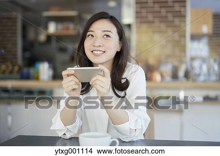 Japanese woman with smartphone in a stylish cafe View Large Photo Image Picture - Japanese woman with smartphone in a stylish cafe. Fotosearch