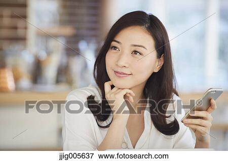 Japanese woman with smartphone in a stylish cafe View Large Photo Image Stock Photo - Japanese woman with smartphone in a stylish cafe. Fotosearch