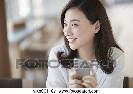 Japanese woman with smartphone in a stylish cafe View Large Photo Image Stock Photo - Japanese woman with smartphone in a stylish cafe. Fotosearch