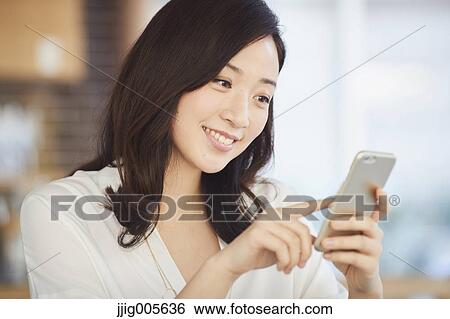 Japanese woman with smartphone in a stylish cafe View Large Photo Image Stock Photograph - Japanese woman with smartphone in a stylish cafe. Fotosearch