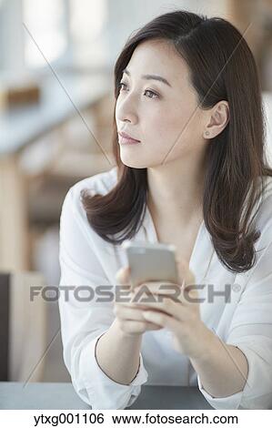 Japanese woman with smartphone in a stylish cafe View Large Photo Image Stock Photograph - Japanese woman with smartphone in a stylish cafe. Fotosearch