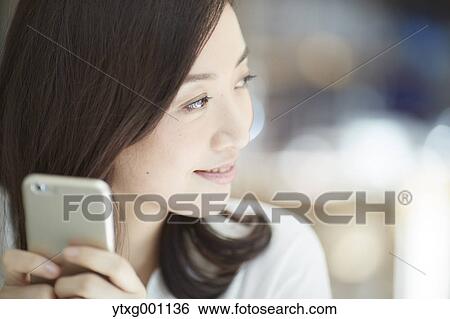 Japanese woman with smartphone in a stylish cafe View Large Photo Image Stock Photograph - Japanese woman with smartphone in a stylish cafe. Fotosearch