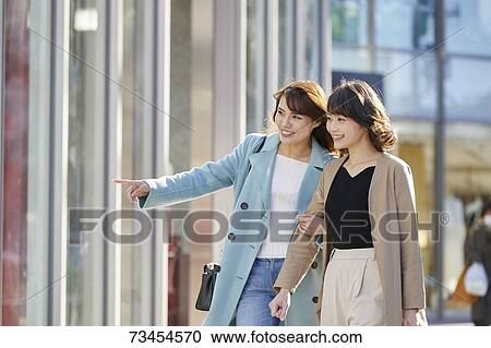 Stock Image - Japanese women window shopping downtown Tokyo. Fotosearch