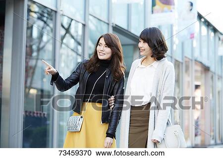 Stock Image - Japanese women window shopping downtown Tokyo. Fotosearch