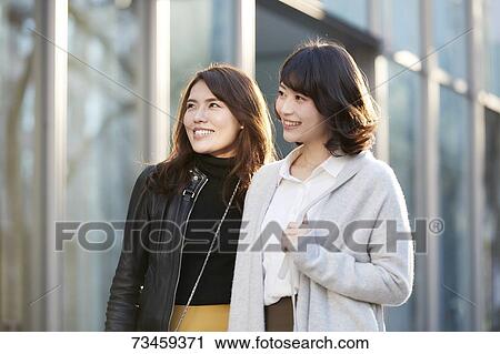 Stock Image - Japanese women window shopping downtown Tokyo. Fotosearch