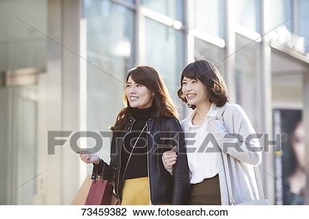 Stock Image - Japanese women window shopping downtown Tokyo. Fotosearch