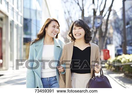 Stock Image - Japanese women window shopping downtown Tokyo. Fotosearch