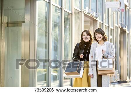 Stock Photograph - Japanese women window shopping downtown Tokyo. Fotosearch