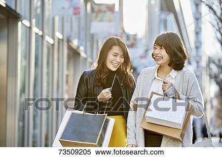 Stock Photography - Japanese women window shopping downtown Tokyo. Fotosearch