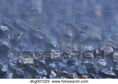 Long exposure of black rocks in the water View Large Photo Image Stock Photography - Long exposure of black rocks in the water. Fotosearch