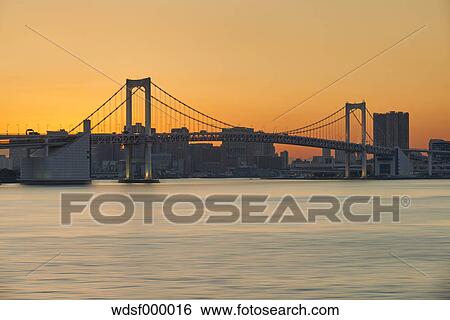 Stock Photograph - Long exposure shot of Rainbow Bridge at sunset, Tokyo, Japan. Fotosearch