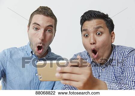 Stock Image - Multi-ethnic men using smartphone. Fotosearch