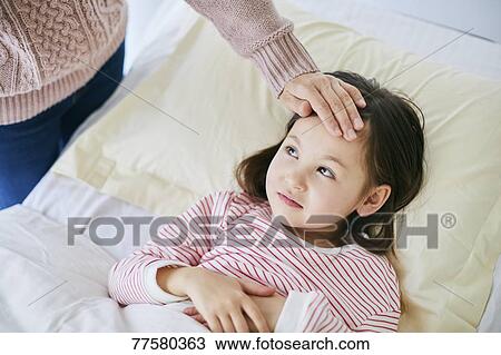 Stock Image - Sick Japanese kid in bed. Fotosearch