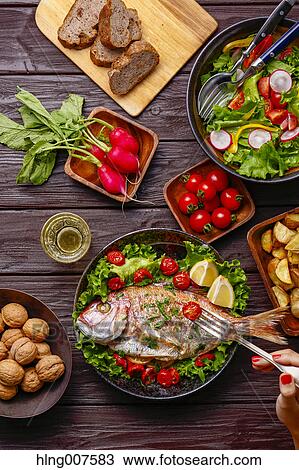 Woman eating grilled fish from table with colorful dishes View Large Photo Image Stock Image - Woman eating grilled fish from table with colorful dishes. Fotosearch