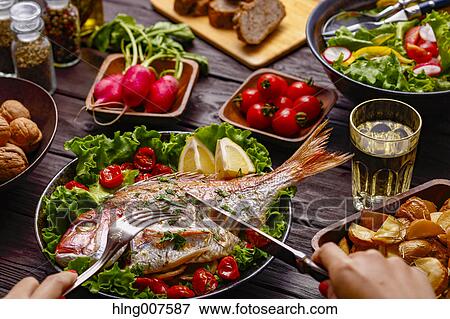 Woman eating grilled fish from table with colorful dishes View Large Photo Image Stock Photo - Woman eating grilled fish from table with colorful dishes. Fotosearch