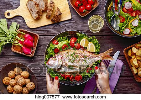 Woman hand serving grilled fish on table with colorful dishes View Large Photo Image Stock Photo - Woman hand serving grilled fish on table with colorful dishes. Fotosearch