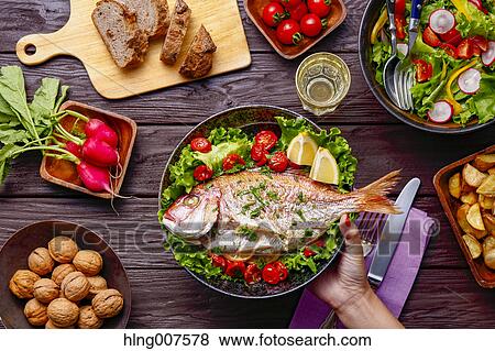 Woman hand serving grilled fish on table with colorful dishes View Large Photo Image Stock Photo - Woman hand serving grilled fish on table with colorful dishes. Fotosearch