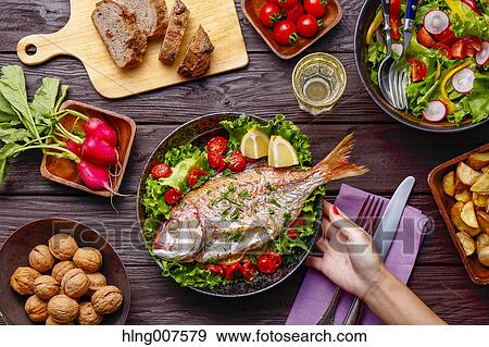 Woman hand serving grilled fish on table with colorful dishes View Large Photo Image Stock Photo - Woman hand serving grilled fish on table with colorful dishes. Fotosearch