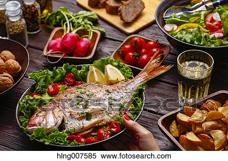 Woman hand serving grilled fish on table with colorful dishes View Large Photo Image Stock Photography - Woman hand serving grilled fish on table with colorful dishes. Fotosearch