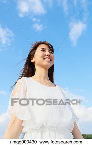Young Japanese woman against blue sky View Large Photo Image Stock Image - Young Japanese woman against blue sky. Fotosearch