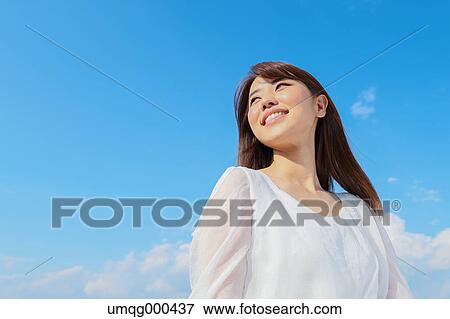 Stock Photo - Young Japanese woman against blue sky. Fotosearch