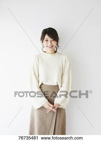 Stock Image - Young Japanese woman against white wall. Fotosearch