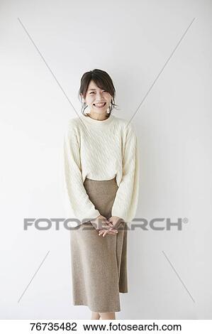 Stock Image - Young Japanese woman against white wall. Fotosearch