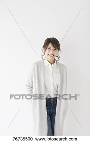 Stock Image - Young Japanese woman against white wall. Fotosearch