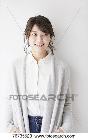 Stock Image - Young Japanese woman against white wall. Fotosearch
