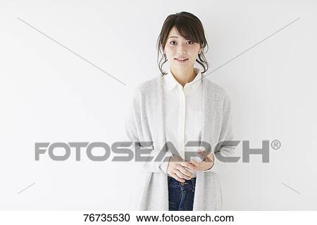 Stock Image - Young Japanese woman against white wall. Fotosearch
