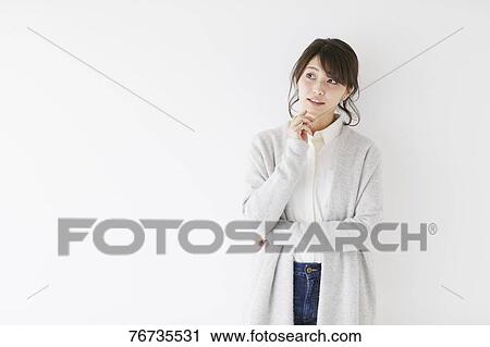 Stock Image - Young Japanese woman against white wall. Fotosearch