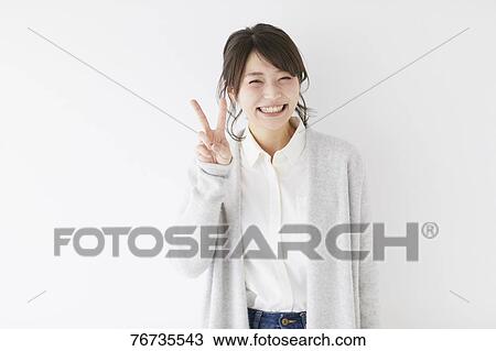 Stock Image - Young Japanese woman against white wall. Fotosearch