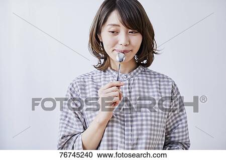 Stock Image - Young Japanese woman eating cake. Fotosearch