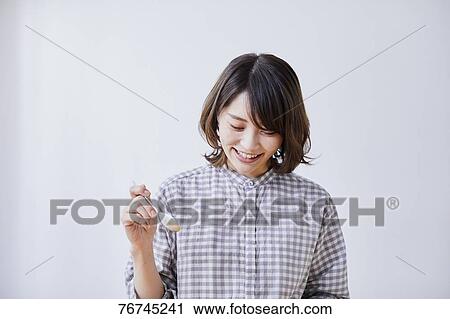 Stock Image - Young Japanese woman eating cake. Fotosearch