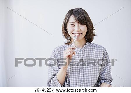 Stock Photo - Young Japanese woman eating cake. Fotosearch