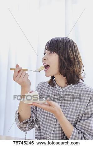 Stock Photography - Young Japanese woman eating cake. Fotosearch