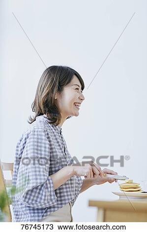 Stock Image - Young Japanese woman eating pancakes. Fotosearch