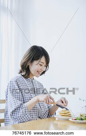 Stock Photograph - Young Japanese woman eating pancakes. Fotosearch