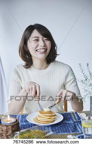 Stock Photograph - Young Japanese woman eating pancakes. Fotosearch