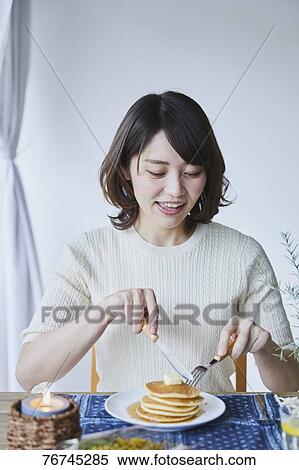 Stock Photography - Young Japanese woman eating pancakes. Fotosearch