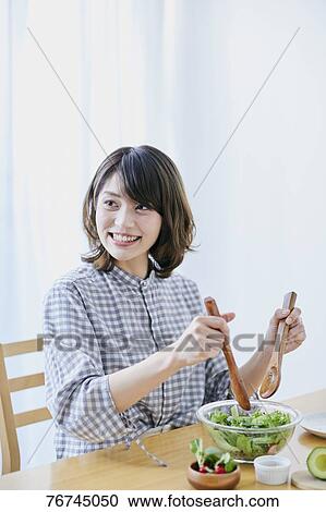 Stock Image - Young Japanese woman eating salad. Fotosearch