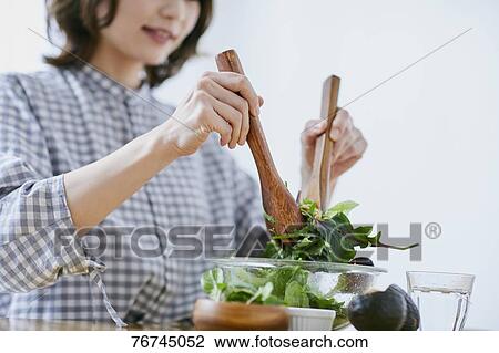 Stock Image - Young Japanese woman eating salad. Fotosearch