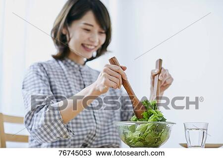 Stock Image - Young Japanese woman eating salad. Fotosearch