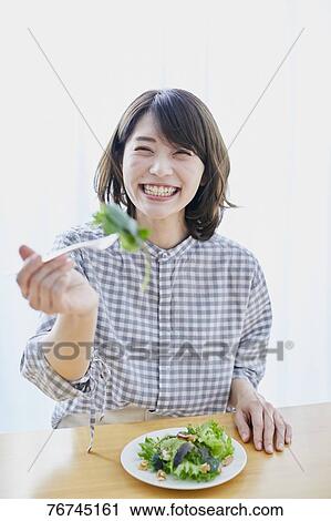 Stock Image - Young Japanese woman eating salad. Fotosearch