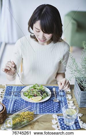 Stock Image - Young Japanese woman eating salad. Fotosearch