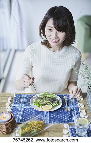 Stock Image - Young Japanese woman eating salad. Fotosearch