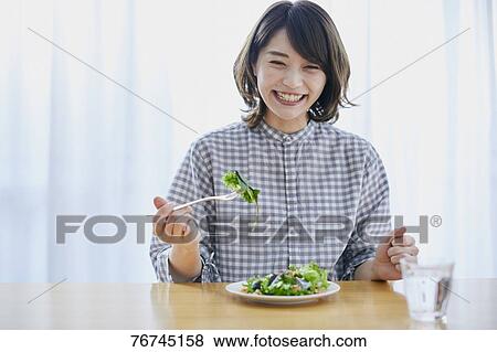 Stock Photo - Young Japanese woman eating salad. Fotosearch