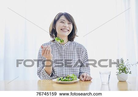 Stock Photo - Young Japanese woman eating salad. Fotosearch